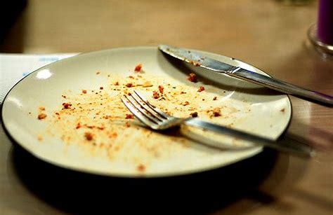 Empty dirty plate with fork and knife on top.